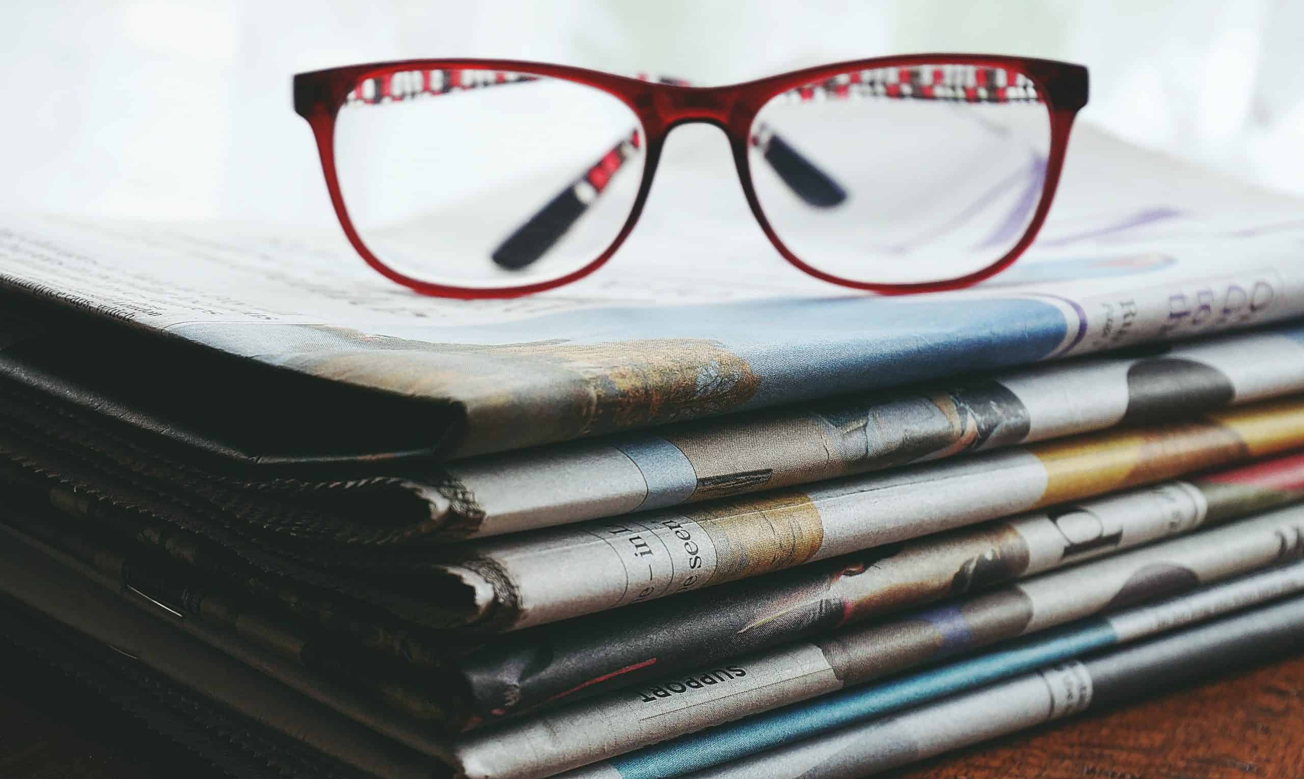 Red framed eyeglasses on newspapers