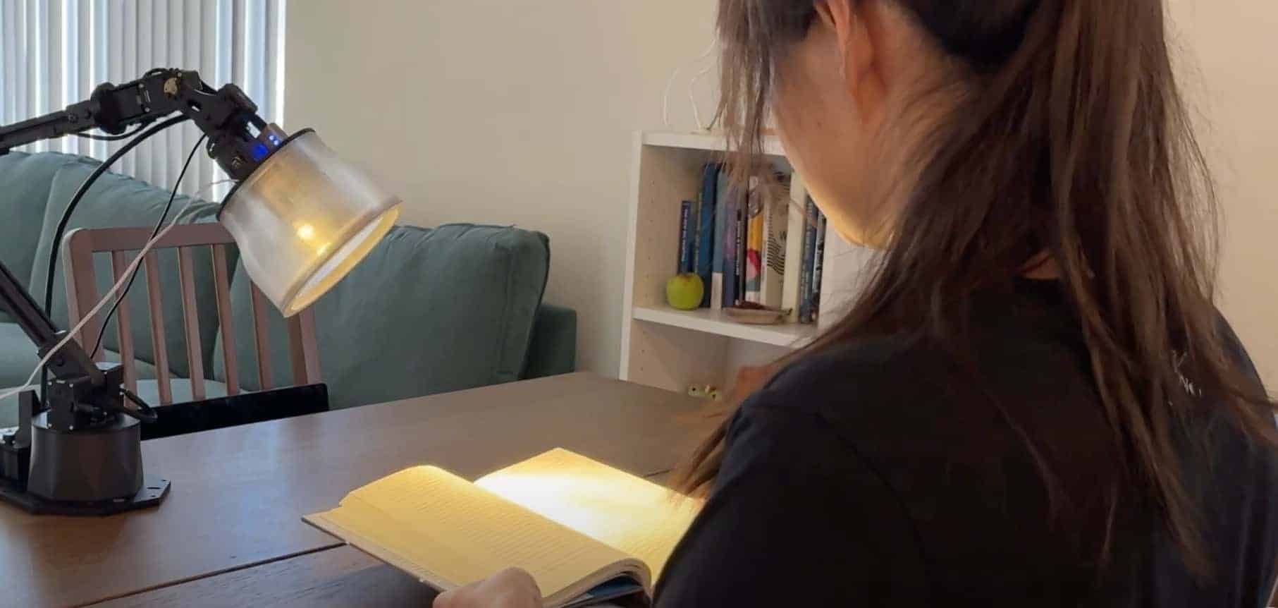 En bild på en kvinna som sitter och läser en bok, upplyst av Apples prototyp på en smart lampa.